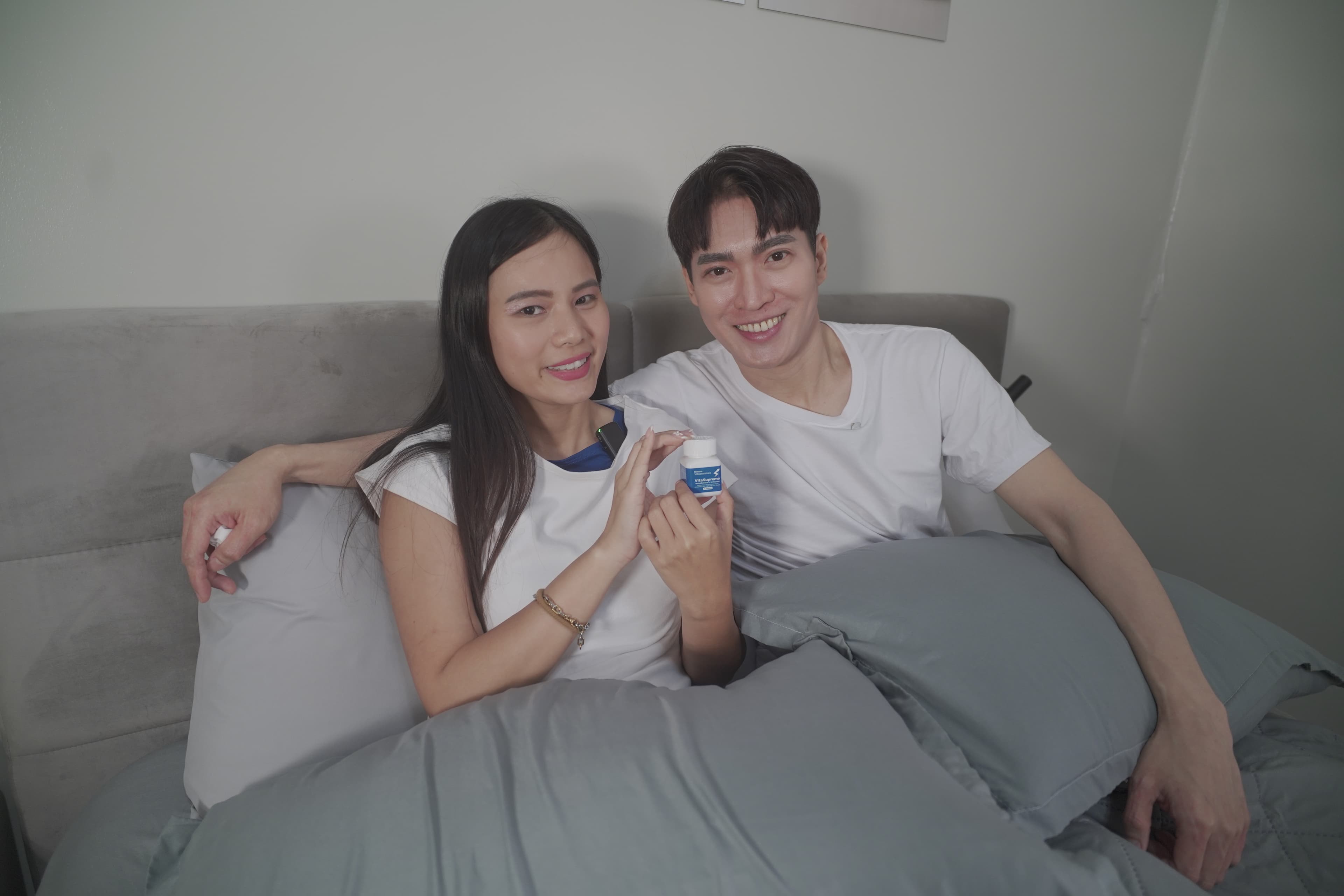 Couple smiling together in bed holding VitaSupremo supplement