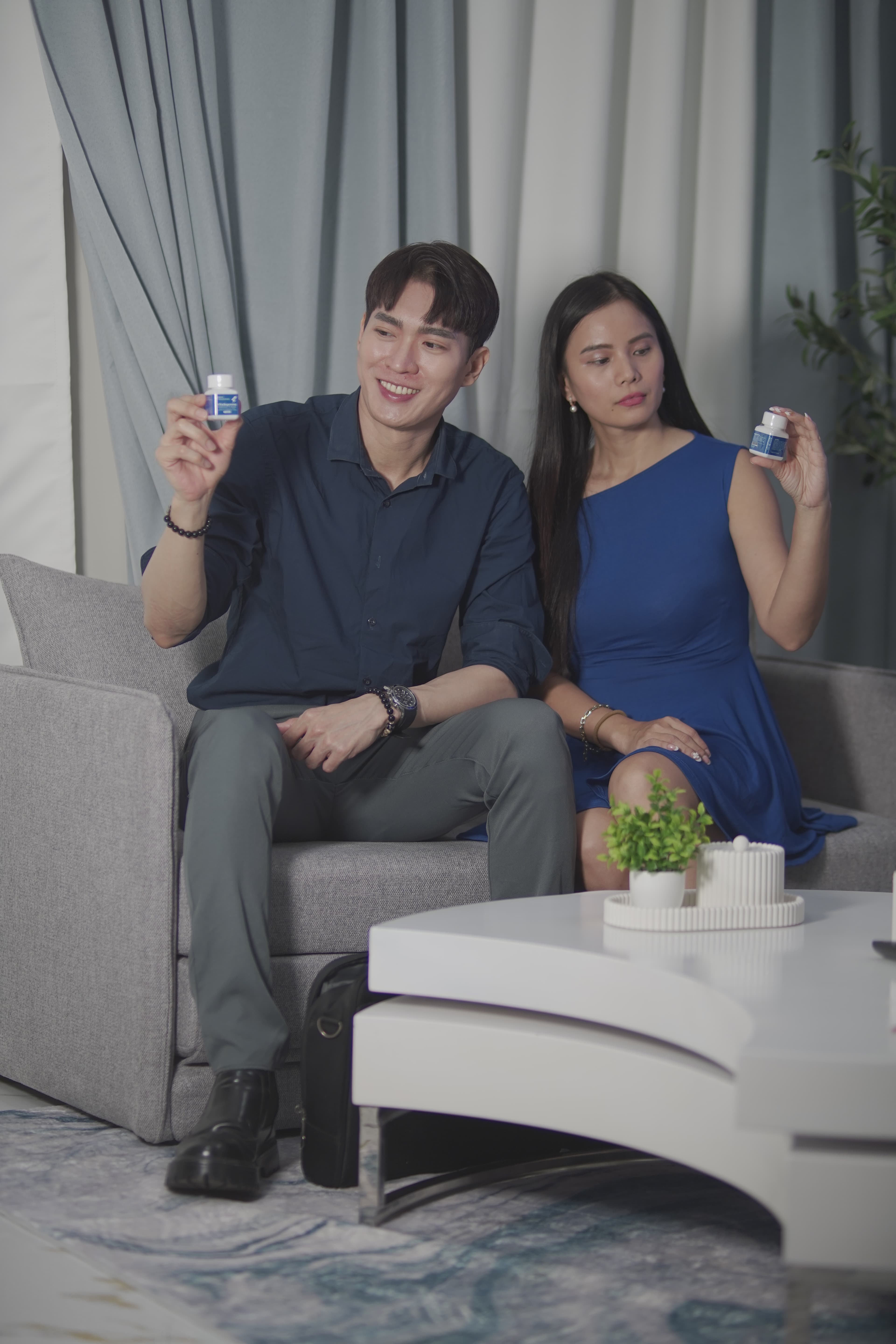 Active couple seated together on sofa holding VitaSupremo bottles